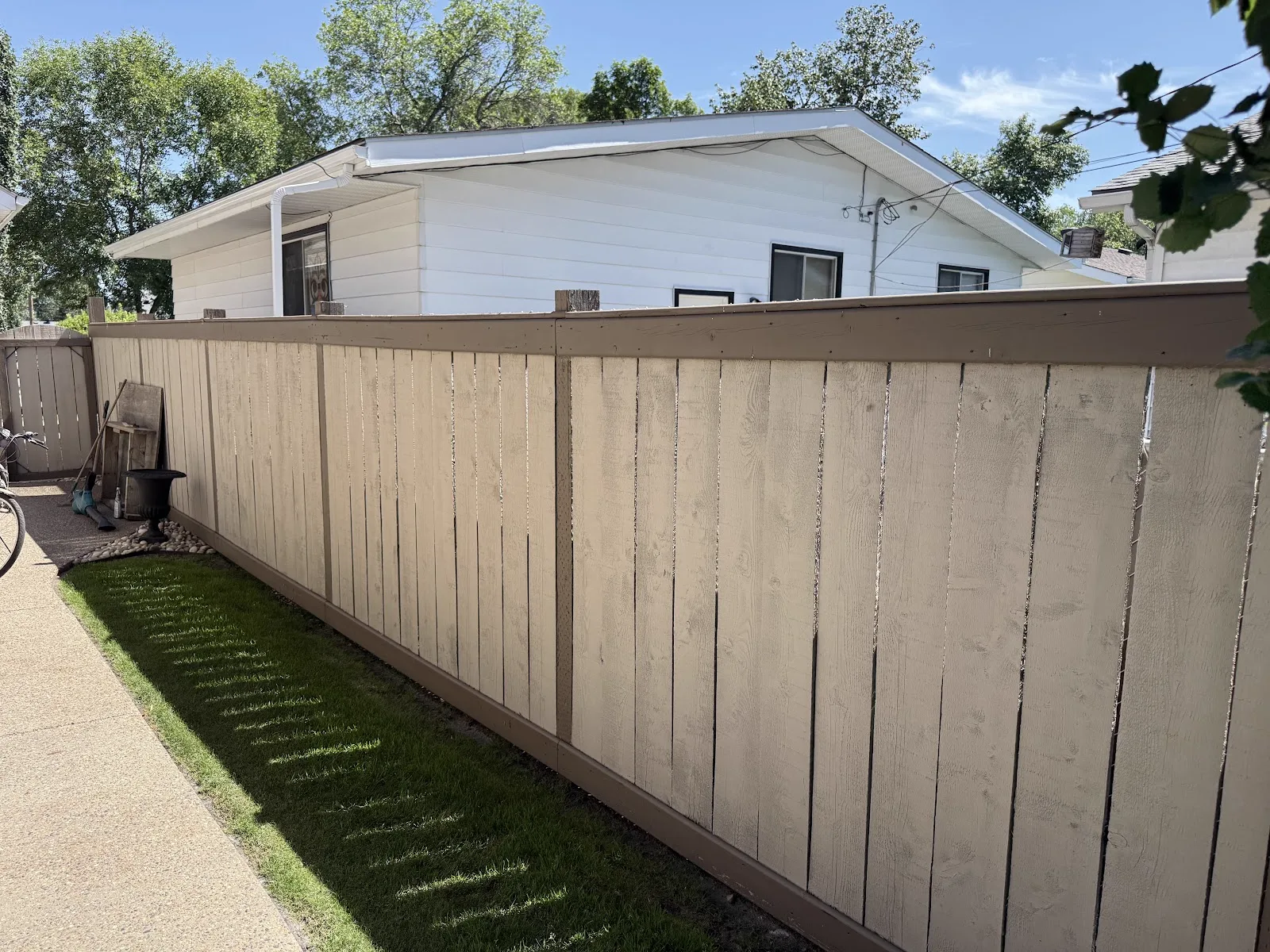 Long run of freshly painted fence along a back alley with matching garage